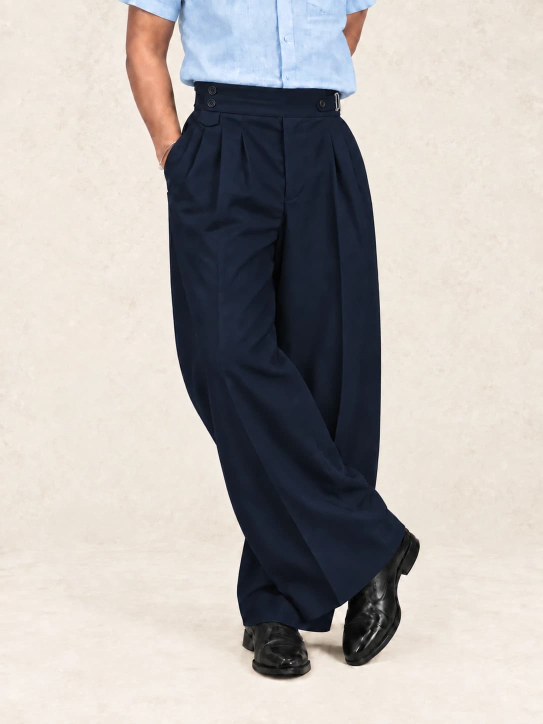 Navy blue pleated trousers — full-length view, standing cross-legged