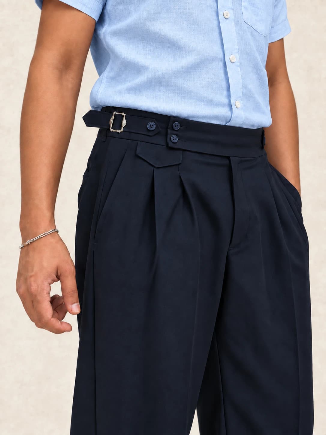 Navy blue pleated trousers — waist detail with buckle side-adjuster